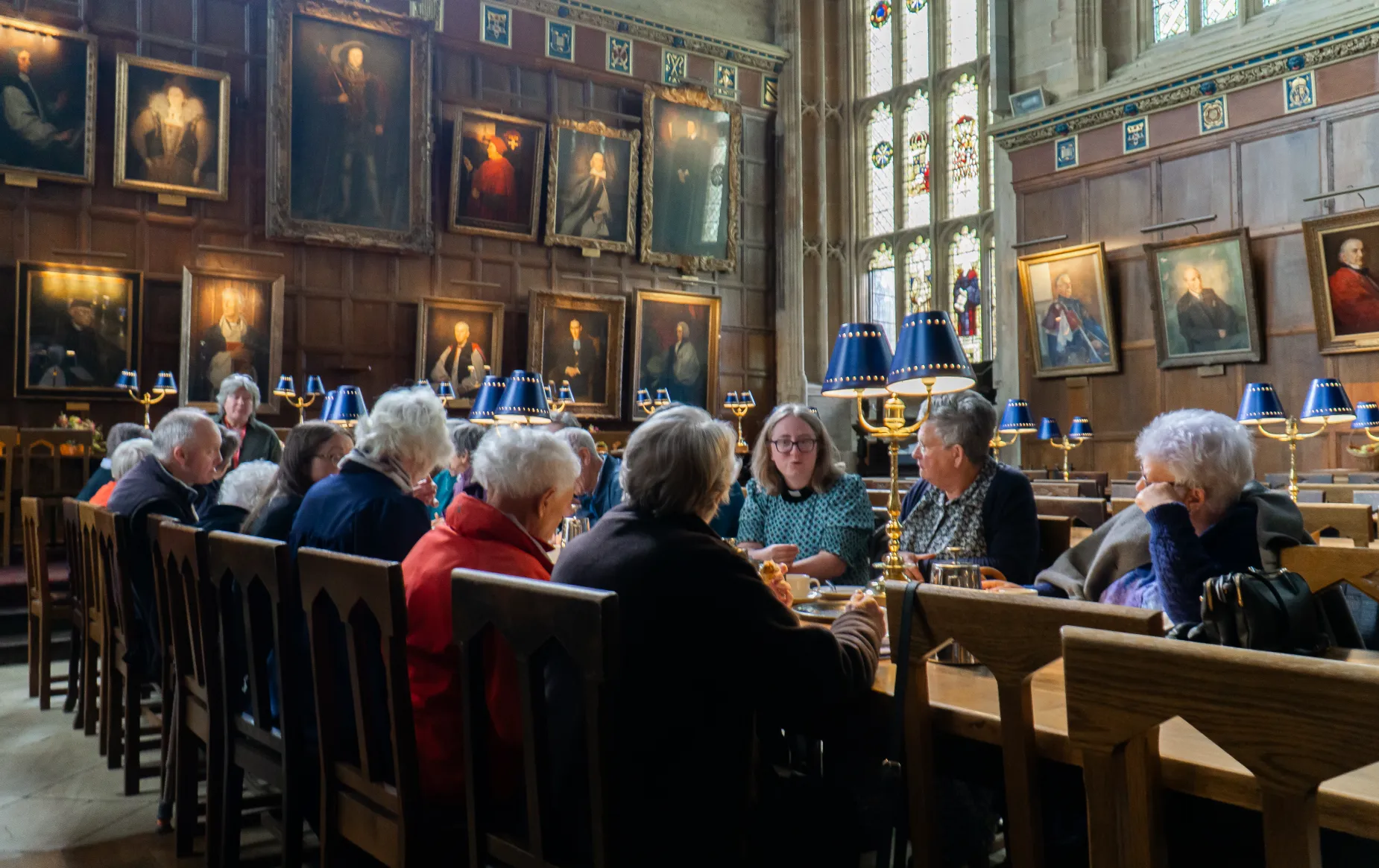 Parish pilgrims sit in the great hall having afternoon tea