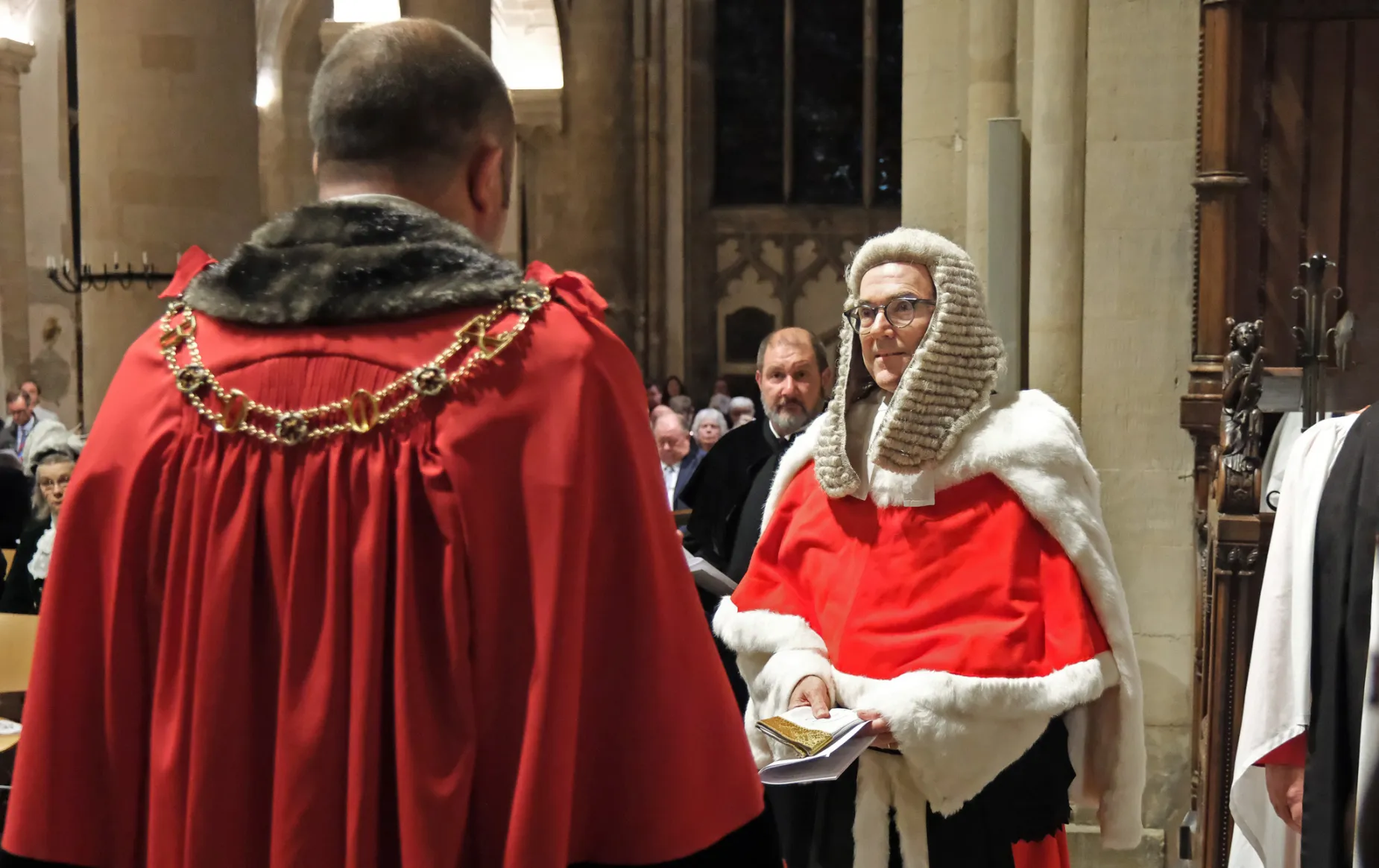 The lord mayor of Oxford, Mike Rolwey, who is wearing his red ceremonial robes and gold mayor's chain, has given a pair of white gloves to Mr Justice Murray, a senior high court judge who is wearing his red fur lined ceremonial cape and a long judge's wig