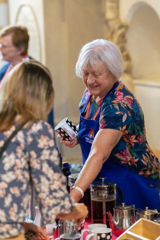 Susan hands a mug of tea to a cathedral visitor