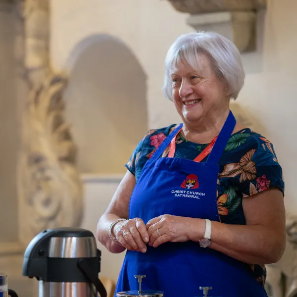 Susan Pagano, a member of the Cathedral refreshments team, wearing her blue cathedral apron and ready to offer you a mug of coffee with a smile