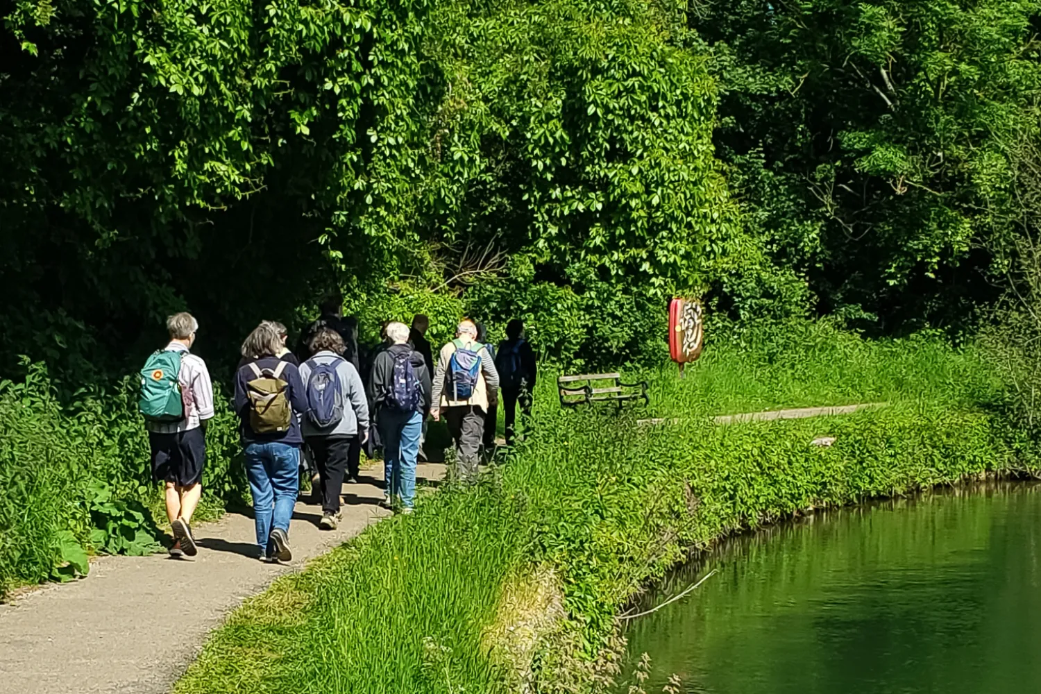 A small group of pilgrims walk past a bend in the river Thames