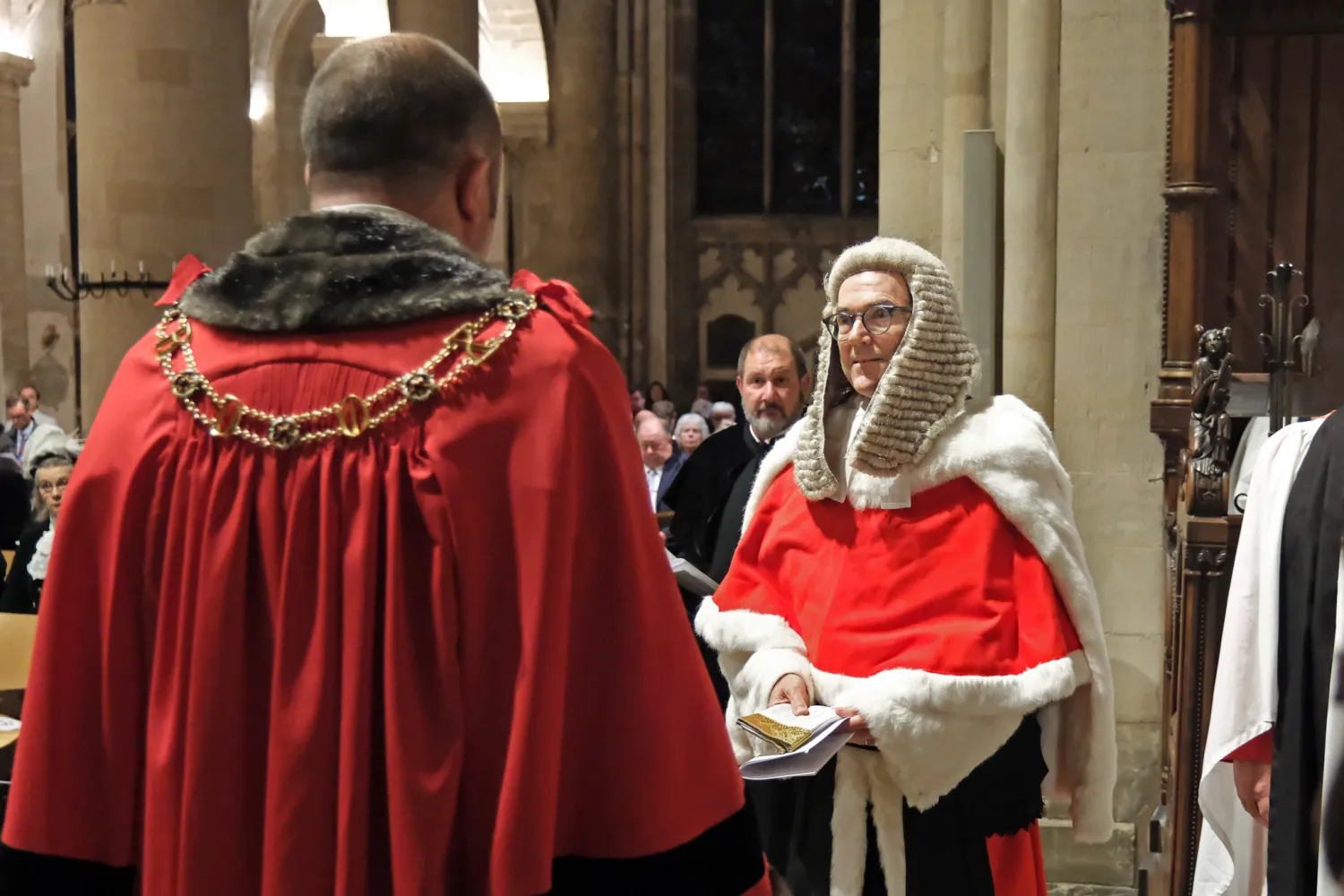 The lord mayor of Oxford, Mike Rolwey, who is wearing his red ceremonial robes and gold mayor's chain, has given a pair of white gloves to Mr Justice Murray, a senior high court judge who is wearing his red fur lined ceremonial cape and a long judge's wig