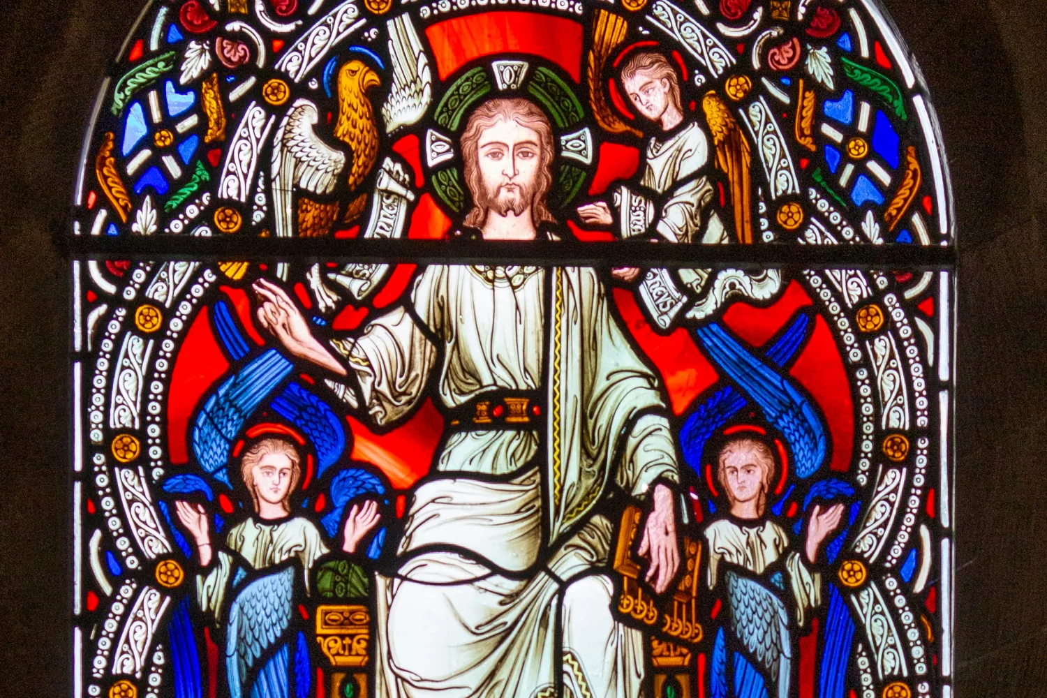 A stained glass window from the Cathedral's chapel of Remembrance, showing jesus sitting on the throne of heaven, flanked by two six winged seraphs