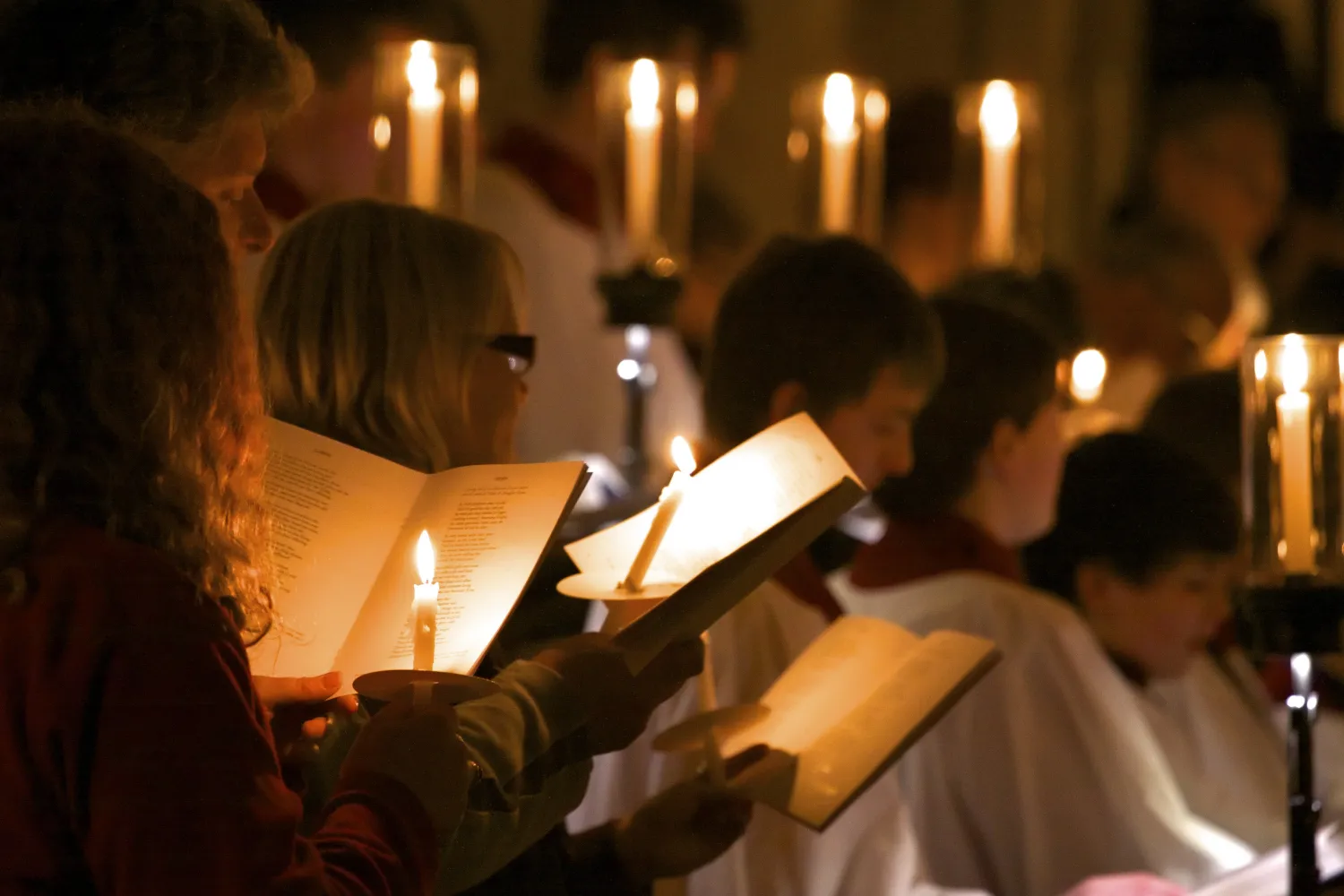 Carol Service attendees use candles to read their orders of service and sing.