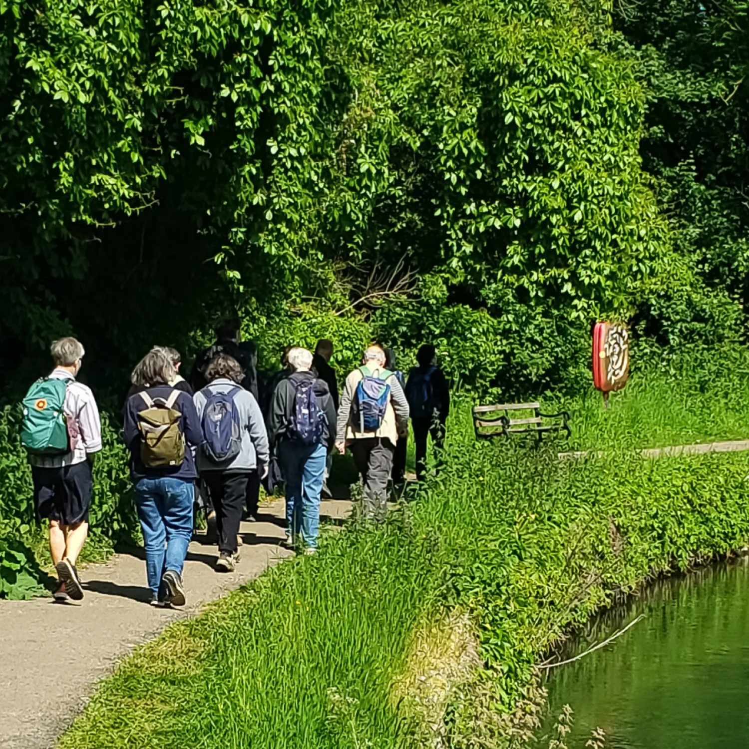 A small group of pilgrims walk past a bend in the river Thames