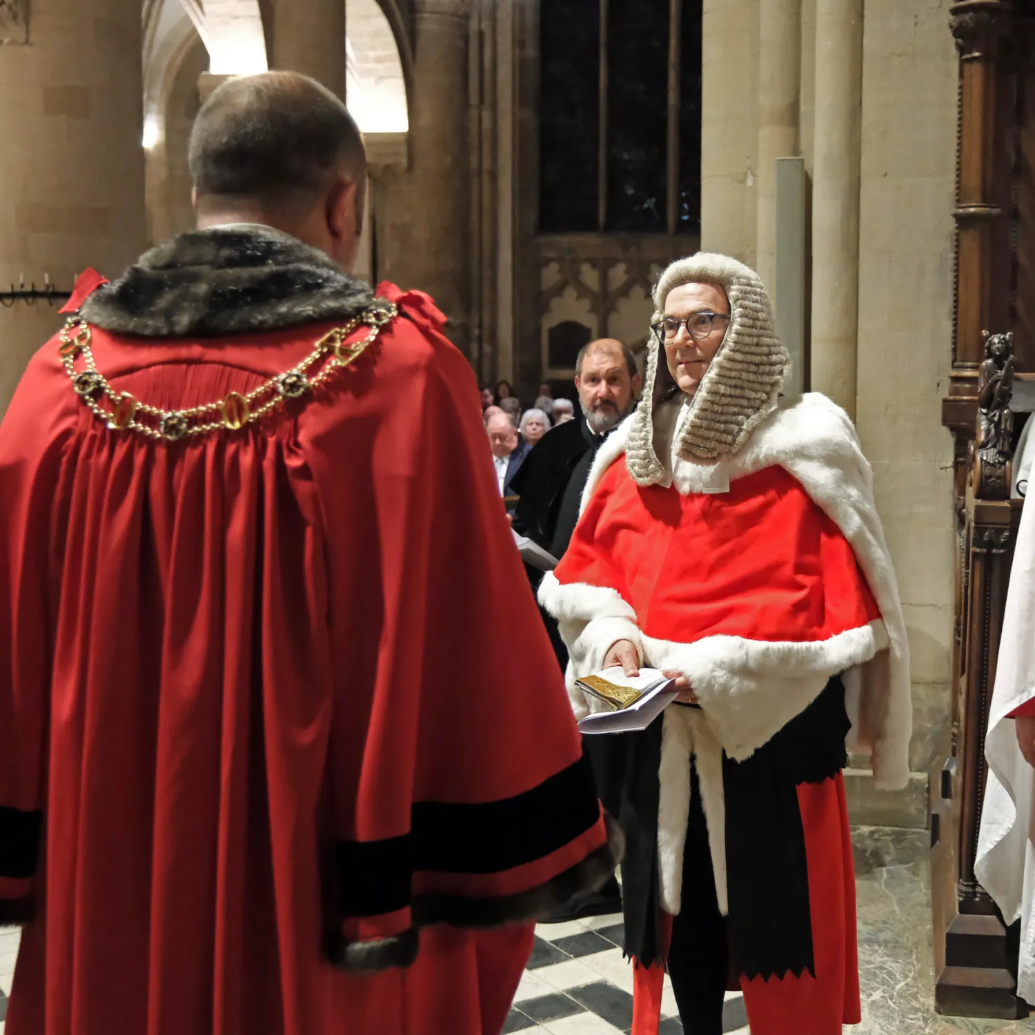 The lord mayor of Oxford, Mike Rolwey, who is wearing his red ceremonial robes and gold mayor's chain, has given a pair of white gloves to Mr Justice Murray, a senior high court judge who is wearing his red fur lined ceremonial cape and a long judge's wig